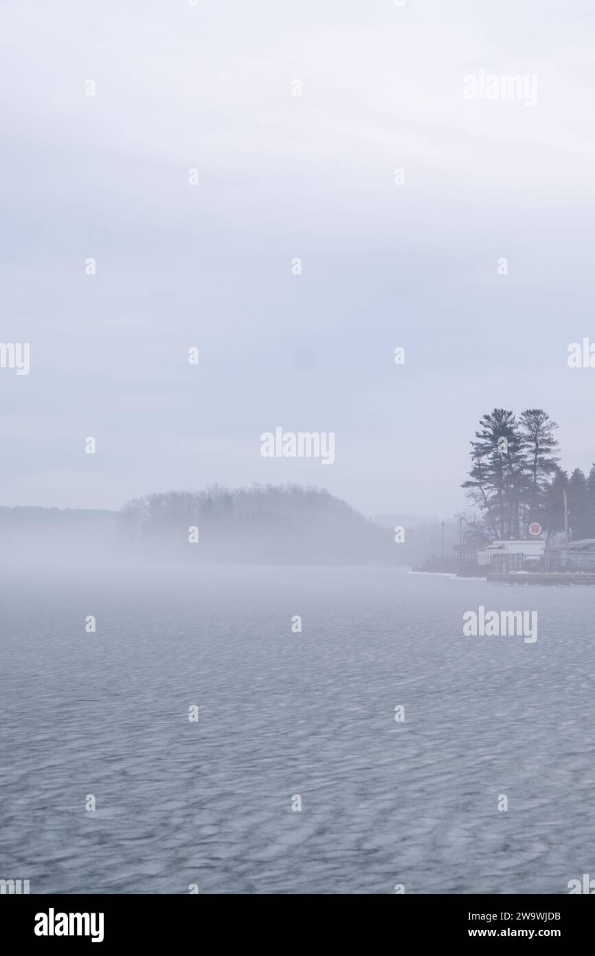 Foto von Rice Lake, Ontario mit nebligem Wetter und gefrorenem Wasser und Silhouette von Kiefern und Hügeln Stockfoto