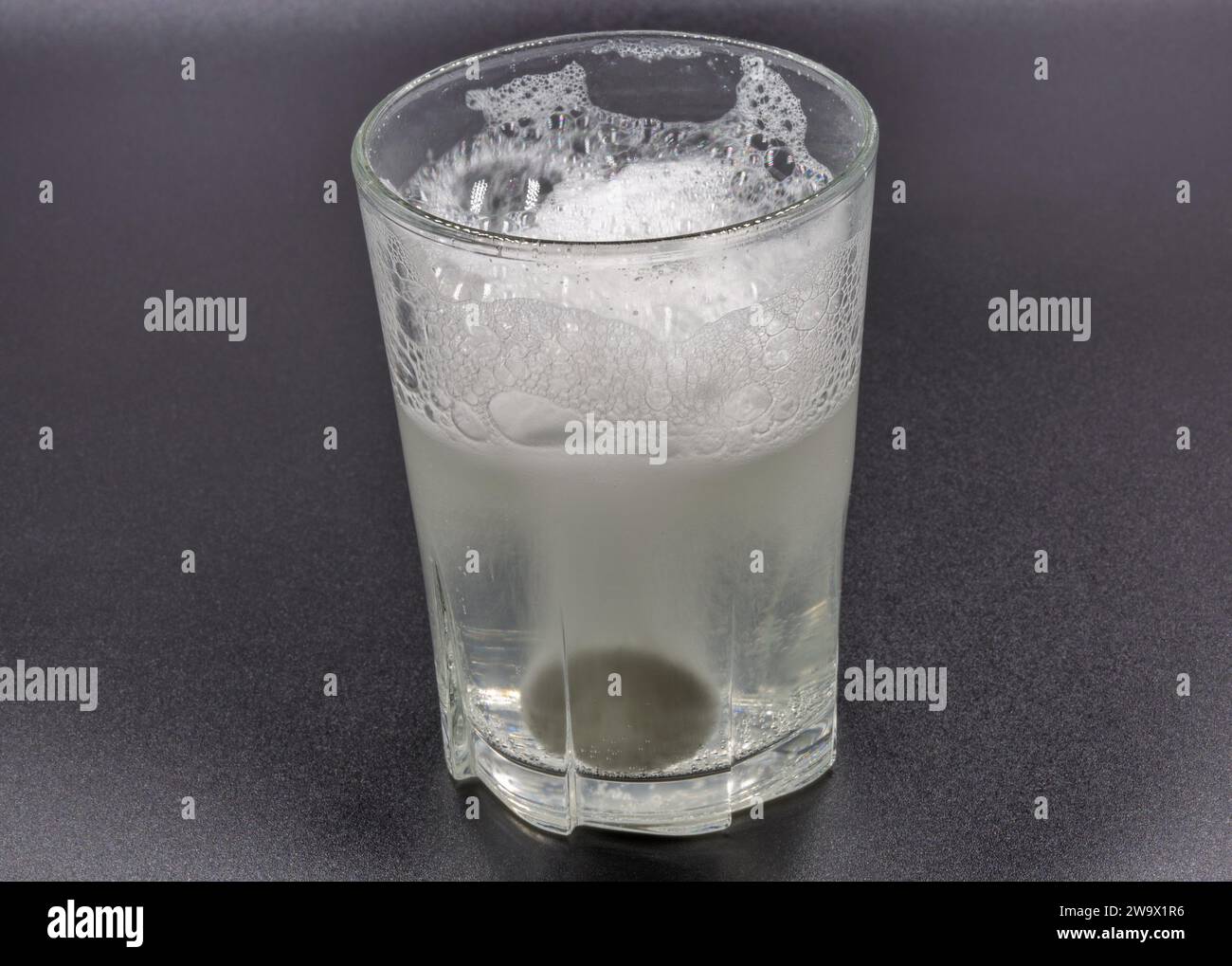 Auflösen von Brausetabletten in einem Glas mit Wassernaht auf Schwarz Stockfoto