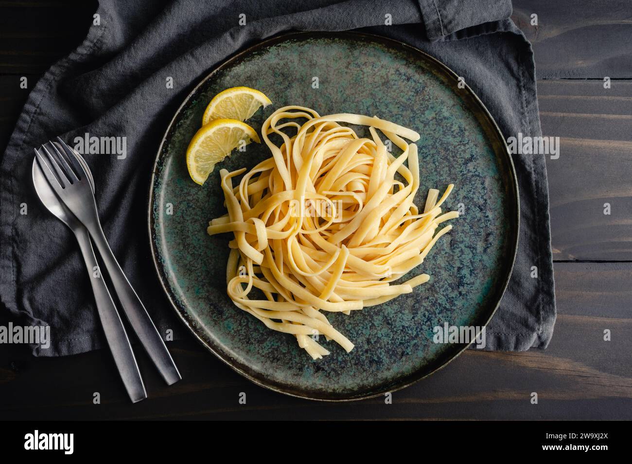 Fettuccine mit Limonen-Mascarponesauce: Ein Teller mit breiten Nudeln, garniert mit Zitronenscheiben Stockfoto