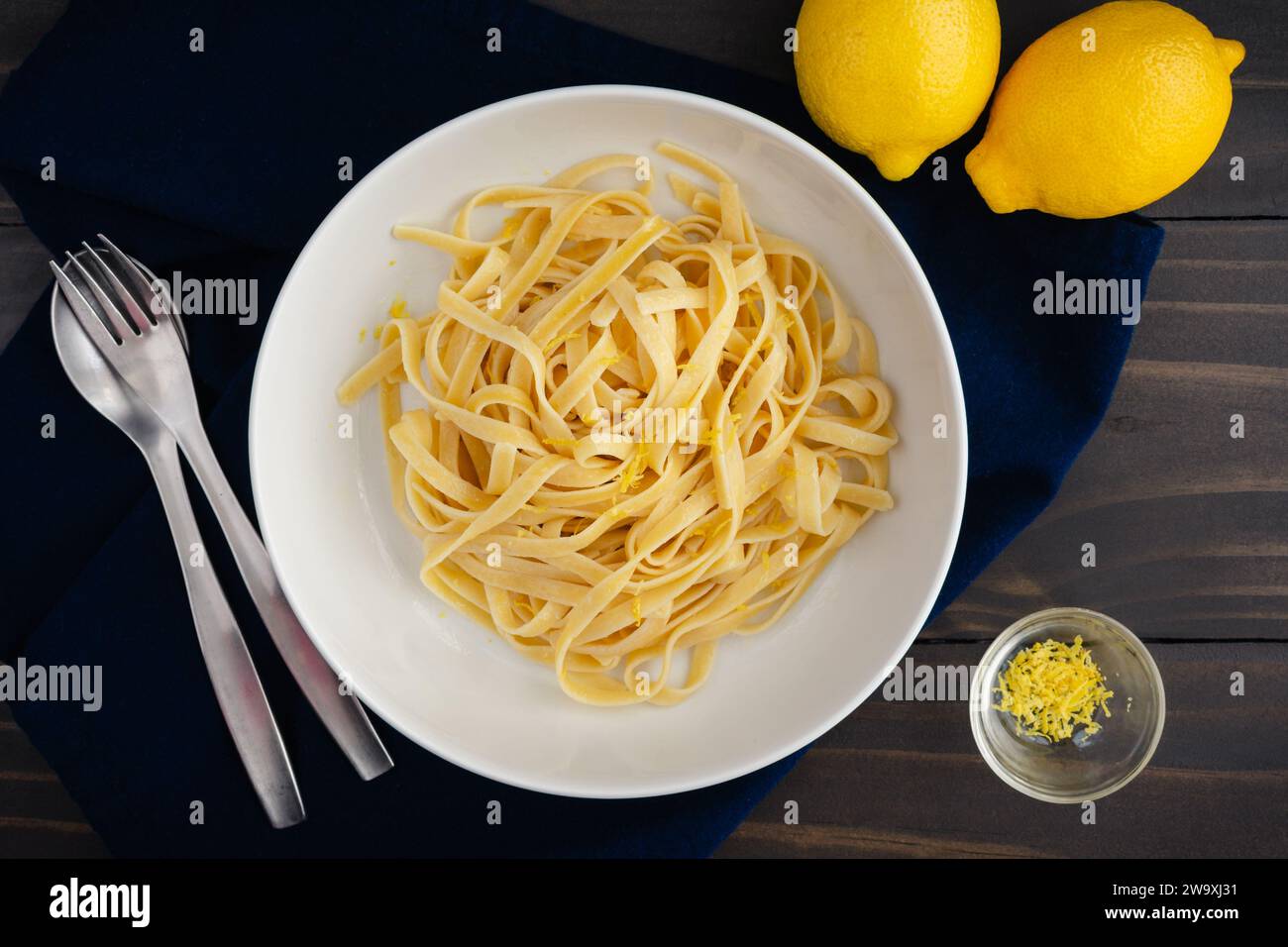 Fettuccine mit Limonen-Mascarponesauce in Pasta Bowl: Breite Nudeln in einer flachen Schüssel serviert und mit Zitronenschale garniert Stockfoto