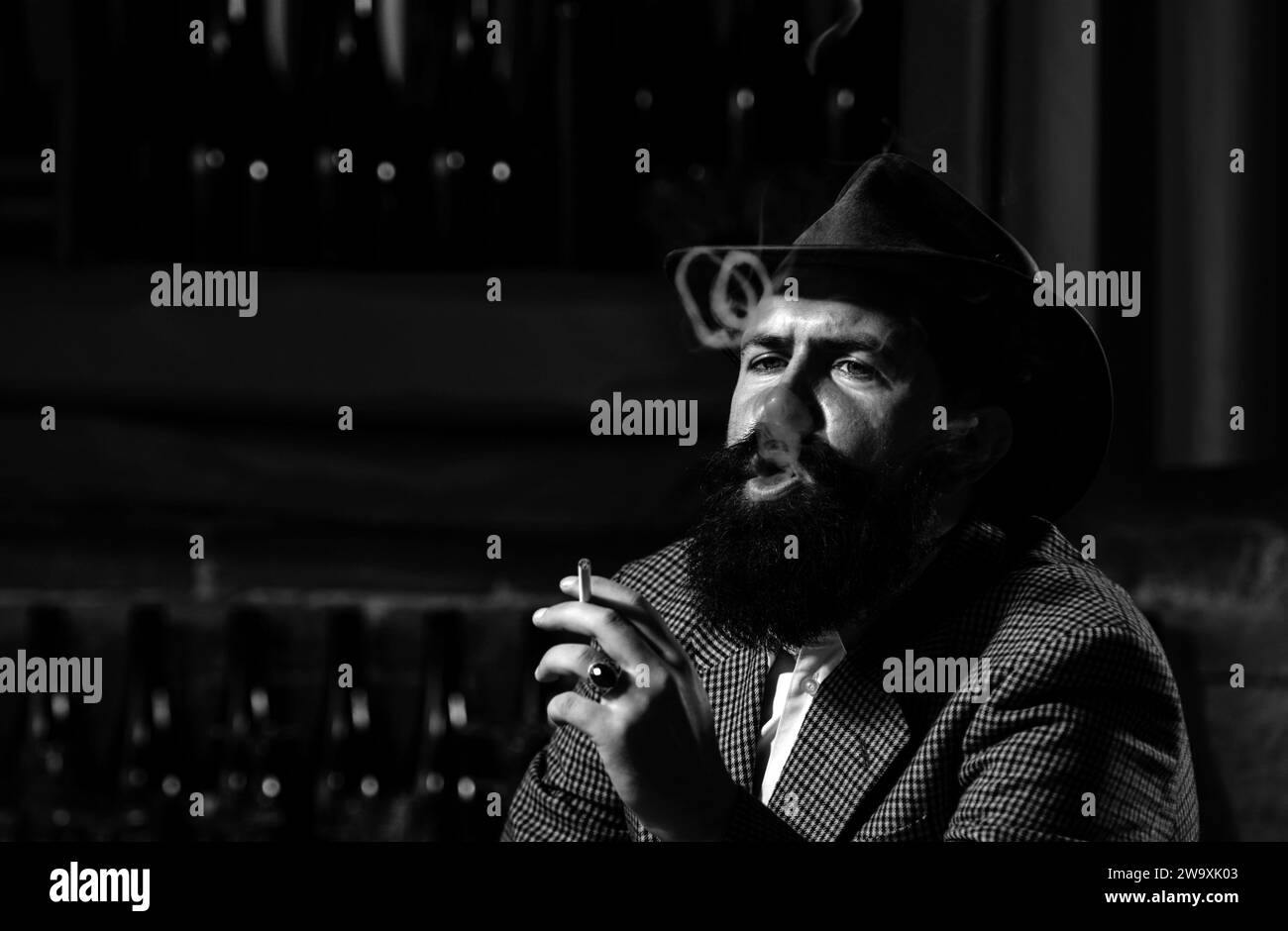 Nahaufnahme eines bärtigen Mannes, der Zigarette raucht und ein Glas Whiskey hält. Stockfoto