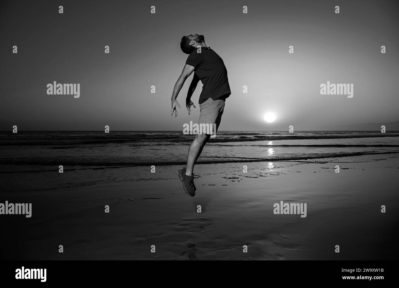 Mann springt am Strand, Silhouette im Sonnenuntergang. Feel Good und Freedom Konzept. Stockfoto