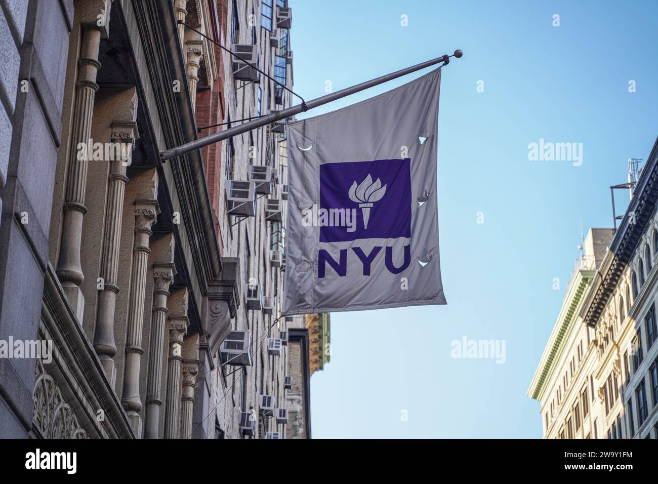 Eine Flagge der New York University hängt an einem Gebäude des Campus. Die New York University (NYU) ist eine renommierte private Forschungsuniversität im Herzen von New York City, bekannt für ihr vielfältiges und dynamisches akademisches Umfeld. Die NYU blickt auf eine reiche Geschichte zurück, die bis ins Jahr 1831 zurückreicht und aus mehreren Schulen, Colleges und Instituten besteht, die eine breite Palette an Bachelor-, Graduiertenprogrammen und professionellen Programmen in verschiedenen Disziplinen wie Kunst, Wissenschaft, Wirtschaft, Recht und mehr anbieten. Der städtische Campus und globale Outreach-Initiativen bieten Studierenden beispiellose Möglichkeiten für kulturelle Imme Stockfoto