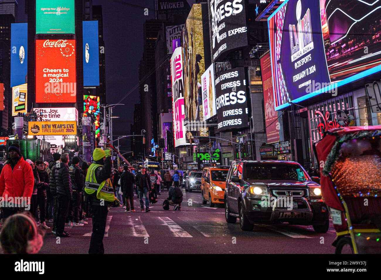 Die Leute laufen auf den Straßen am Times Square und blockieren die Autos. Der Straßenverkehr in New York City ist berühmt für seine geschäftige, temporeiche und oft überfüllte Natur. Das komplizierte Netz von Straßen und Straßen beherbergt ein riesiges Netz von Fahrzeugen, darunter Autos, Taxis, Busse und Fahrräder. alle navigieren in einem Meer von Fußgängern. Tägliche Staus während der Hauptverkehrszeiten sind alltäglich, besonders in der Nähe wichtiger Durchgangsstraßen und Brücken, was zu längeren Pendlerzeiten und gelegentlicher Frustration für Einwohner und Besucher gleichermaßen führt. Stockfoto