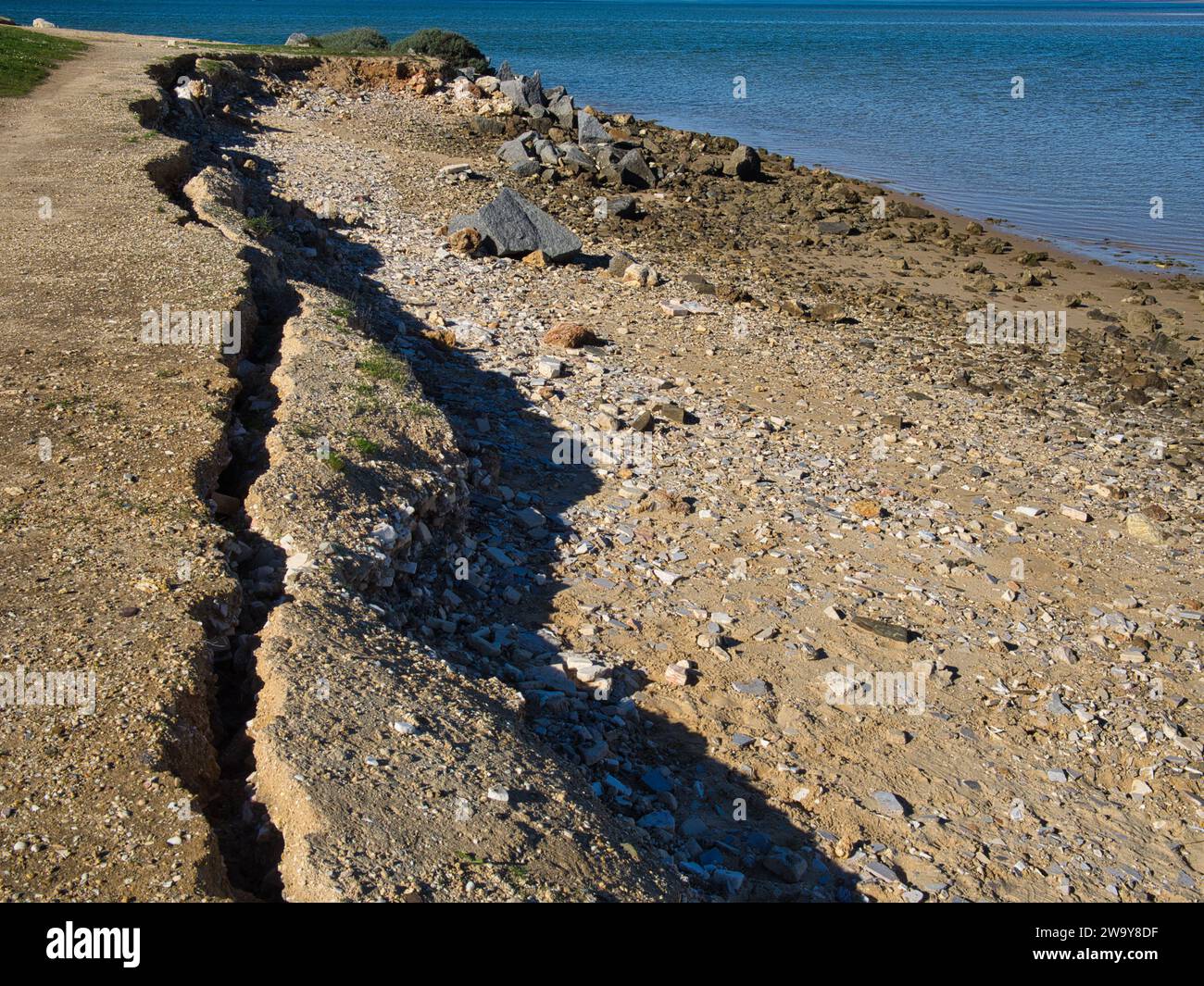 Erosion in der Küstenzone. Der Boden bricht und rutscht ins Meer. Stockfoto