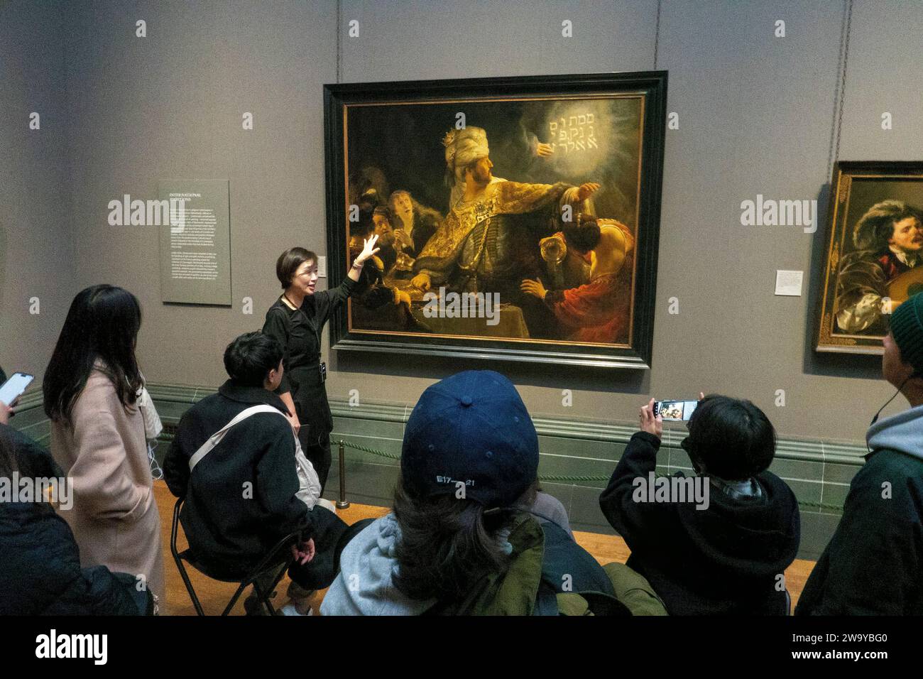 Japanische Tourgruppe, die Rembrandts Belshazzar's Feast, National Gallery, London, Großbritannien besichtigt Stockfoto