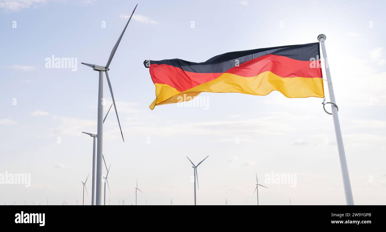 Deutsche Flagge flattert im Hinterland von Windrädern Symbol für nachhaltige Entwicklung Bundesrepublik Deutschland. Stockfoto