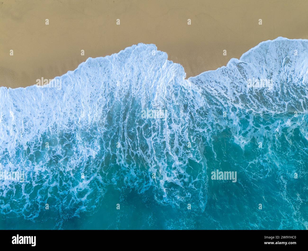 Ein Blick von oben auf den goldenen Sand Rotonda Beach in Tropea mit türkisfarbenem Wasser und Wellen, die an Land krachen Stockfoto