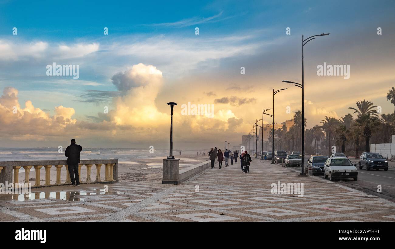 In der Abenddämmerung laufen die Menschen entlang der Promenade am Strand Bou Jaafar am Mittelmeer in Sousse, Tunesien. Stockfoto