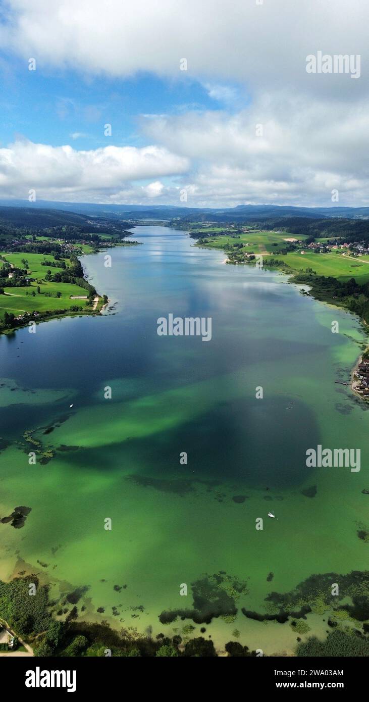Luftbild-Drohnenaufnahme des Lac de Saint-Point (Friedliche glaziale Seewasser und umliegende Hügel in der Nähe von Malbuisson, Doubs, Jura, Frankreich. Stockfoto
