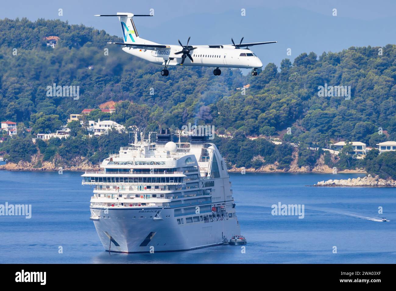 Skiathos, Griechenland - 24. August 2023: Avanti Air Dash 8 mit einem Boot im Hintergrund, das sich dem Flughafen Skiathos nähert Stockfoto
