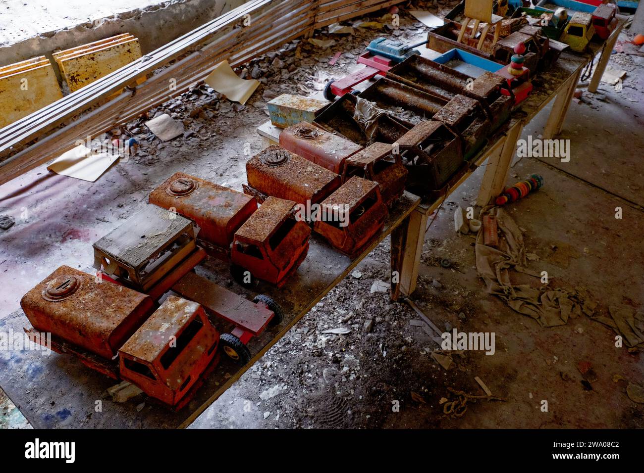 Alte Spielzeugwagen auf einem Tisch in einem Raum, der Anzeichen von Vernachlässigung und Verfall zeigt. Stockfoto