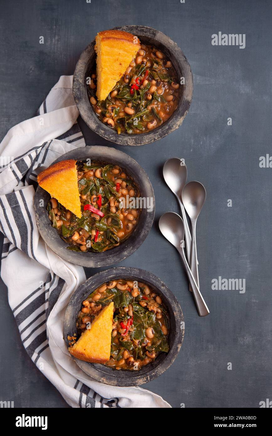 Vegane Blauaugenerbsen aus dem US-Süden, Kohl und Maisbrot, die von oben auf einer grauen Oberfläche mit Kopierraum geschossen werden Stockfoto