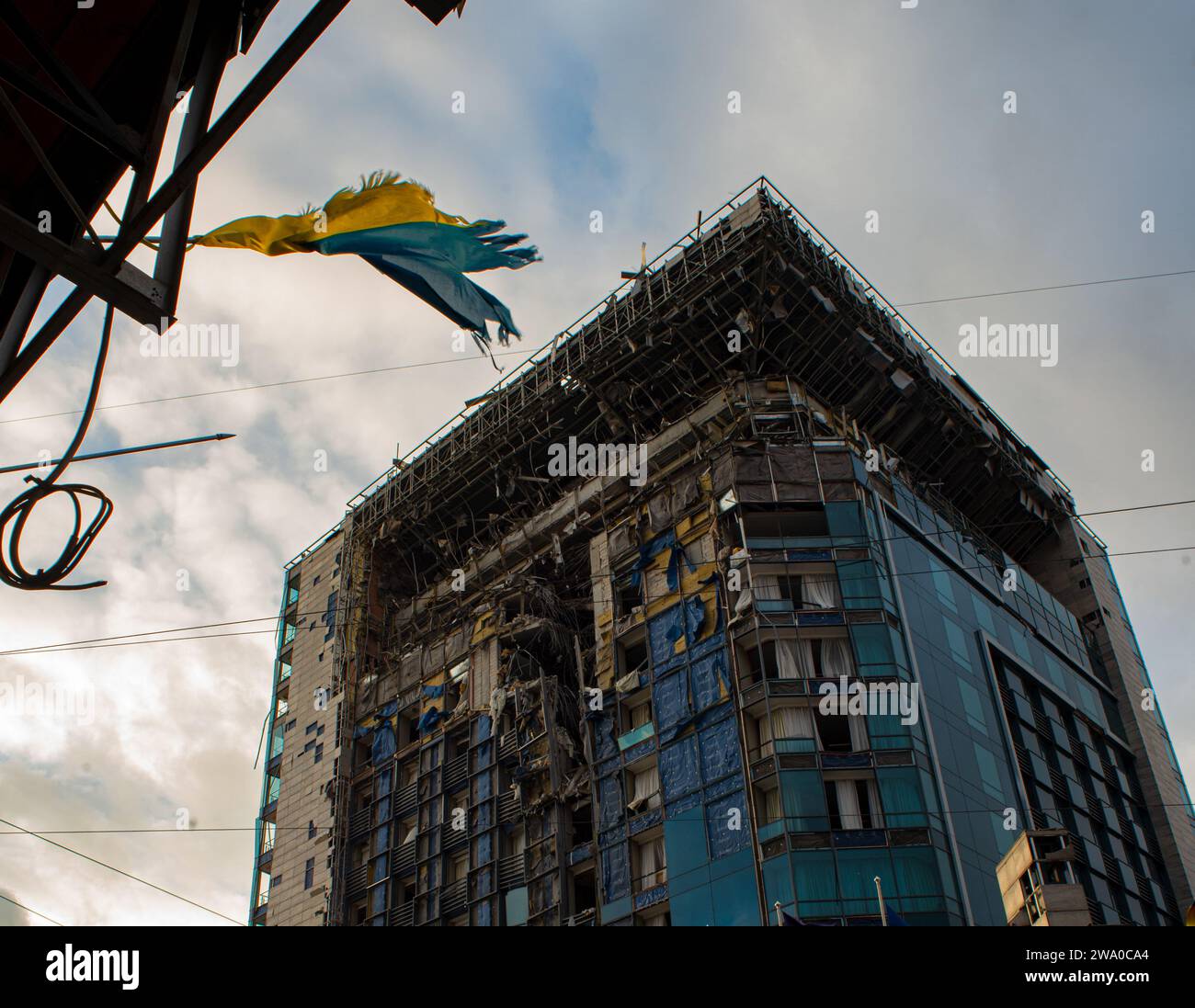 Die gelb-blaue Flagge der Ukraine, gerissen durch die Explosion einer russischen Rakete, die das 5-Sterne-Hotel Charkiw Palace zerstörte Stockfoto