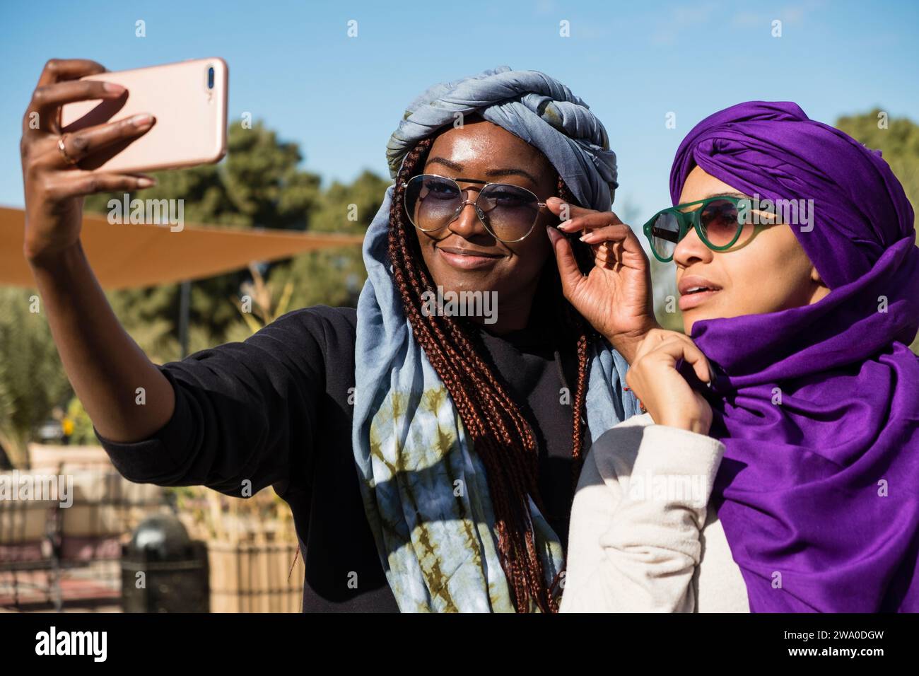 Zwei weibliche Touristen posieren für ein Selfie-Foto ihrer Wüstenschals, Sahara-Wüste, Marokko Stockfoto