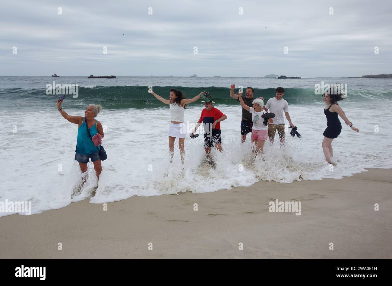 Rio de Janeiro, Rio de Janeiro, Brasilien. Dezember 2023 31. Eine Frau macht ein Selfie, während ihre Familie am Copacabana Beach in Rio de Janeiro gemeinsam über eine Welle springt. Eine brasilianische Tradition für viel Glück: Die Nachtschwärmer springen sieben Mal über die Ozeanwellen und wünschen sich für den Rest des Jahres, damit der Ozean alles wegspülen kann, was Sie nicht mit ins neue Jahr mitnehmen möchten. Sie wünschen 7 Dankbarkeit und Hoffnung für den Rest des kommenden Jahres. (Credit Image: © Bob Karp/ZUMA Press Wire) NUR REDAKTIONELLE VERWENDUNG! Nicht für kommerzielle ZWECKE! Stockfoto