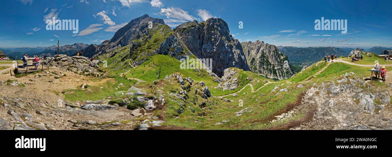 Panoramablick auf eine Berglandschaft mit Wanderern und grünen Hängen unter blauem Himmel, 360° Panorama, Alpspitze, Osterfelderkopf, AlpspiX, Kreuzeck, Ga Stockfoto