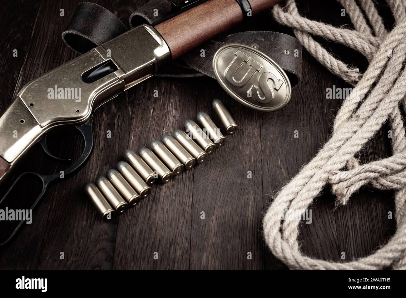 Old West Gun - Repetiergewehr mit Hebelbetätigung und Patronen und US-amerikanischer Bronzestraße auf Holztisch Stockfoto