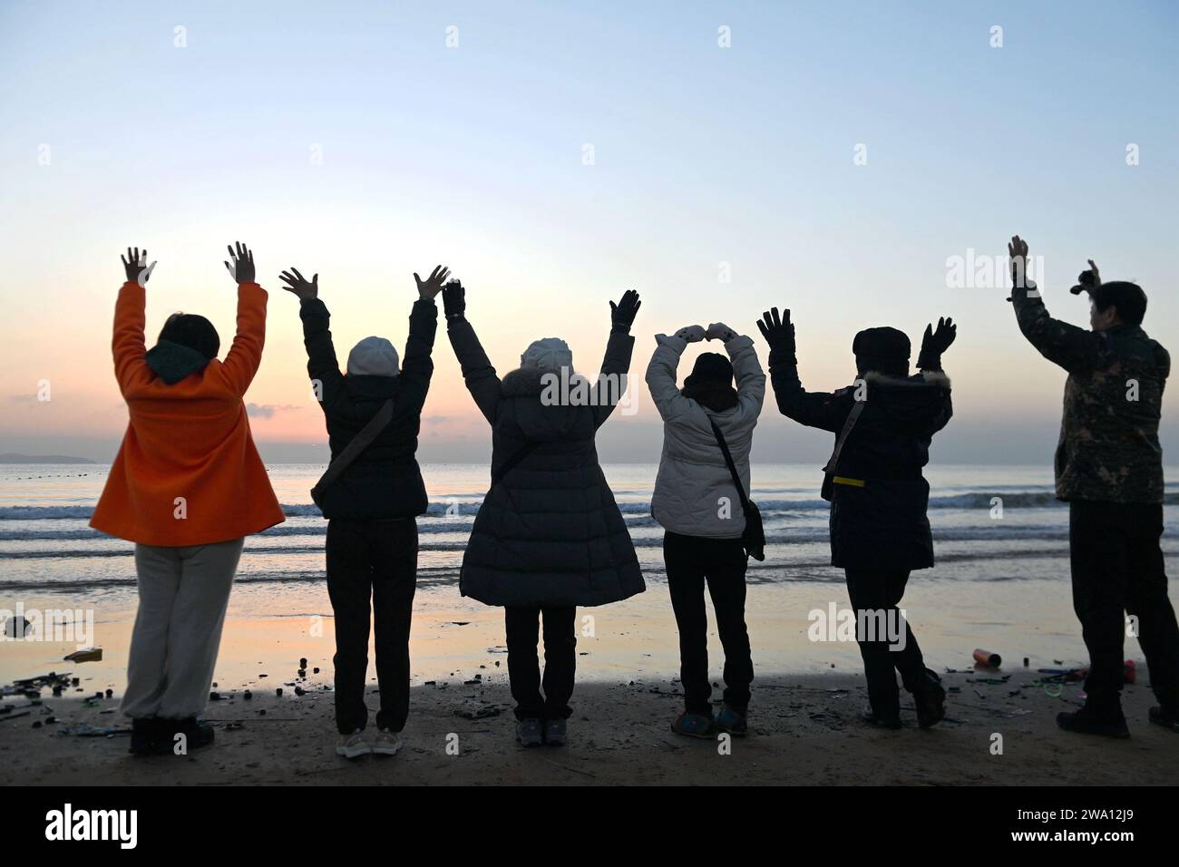 QINGDAO, CHINA - 1. JANUAR 2024 - Touristen begrüßen den Neujahrssonnenaufgang am Golden Beach in Qingdao, Provinz Shandong, China, 1. Januar 2024. Stockfoto