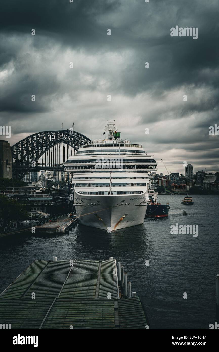 Kolossales Kreuzfahrtschiff, das anmutig im Hafen von Sydney vor Anker liegt, mit der weltberühmten Sydney Harbour Bridge als atemberaubender Kulisse Stockfoto