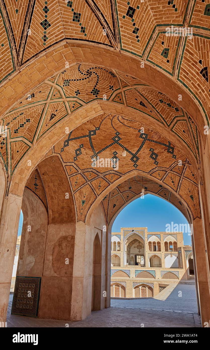 Blick auf das Haupteingangstor der Agha Bozorg Moschee aus dem 18. Jahrhundert durch Bögen des Hauptgebäudes. Kaschan, Iran. Stockfoto