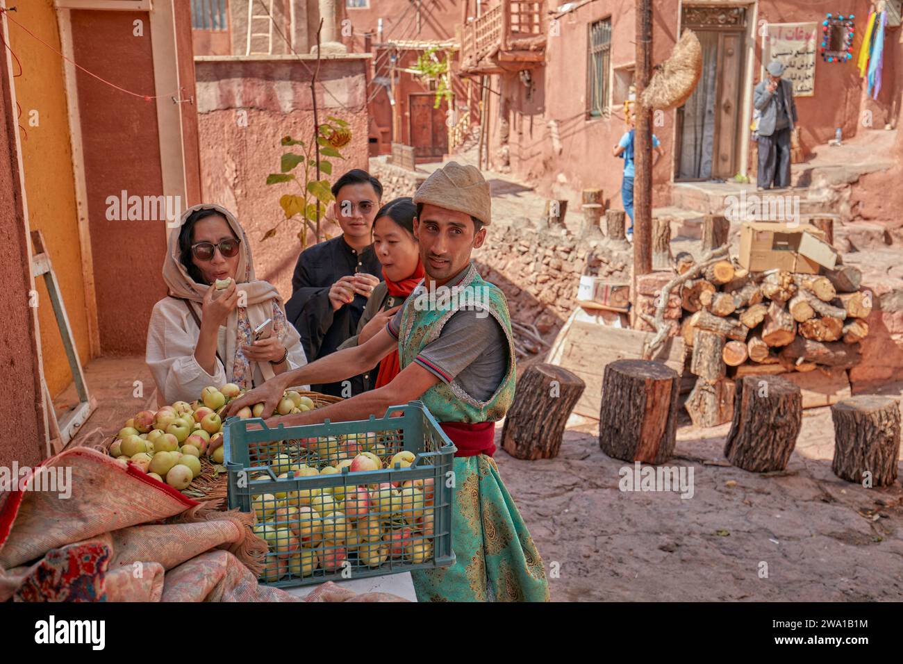 Chinesische Touristen kaufen frische Äpfel von einem lokalen Straßenverkäufer im historischen Dorf Abyaneh, Natanz County, Iran. Stockfoto