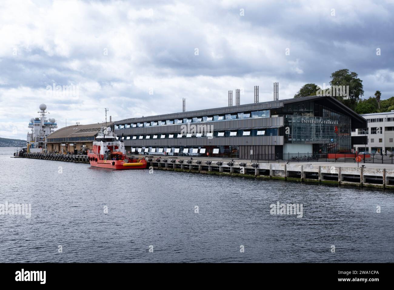 Boot im Hafen am Pier am University of Tasmania-Gebäude in Hobart, Tasmanien. Bewölkter Himmel. Abfahrtsort für das Boot nach MONA Stockfoto