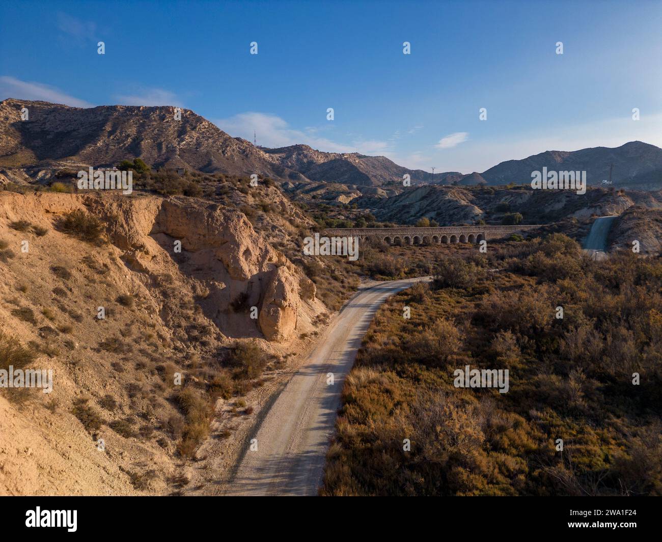 Feldweg in trockener Wüstenlandschaft mit fernen Klippen und Morgensonnenlicht, Elche, Provinz Alicante, Spanien – Stockfoto Stockfoto
