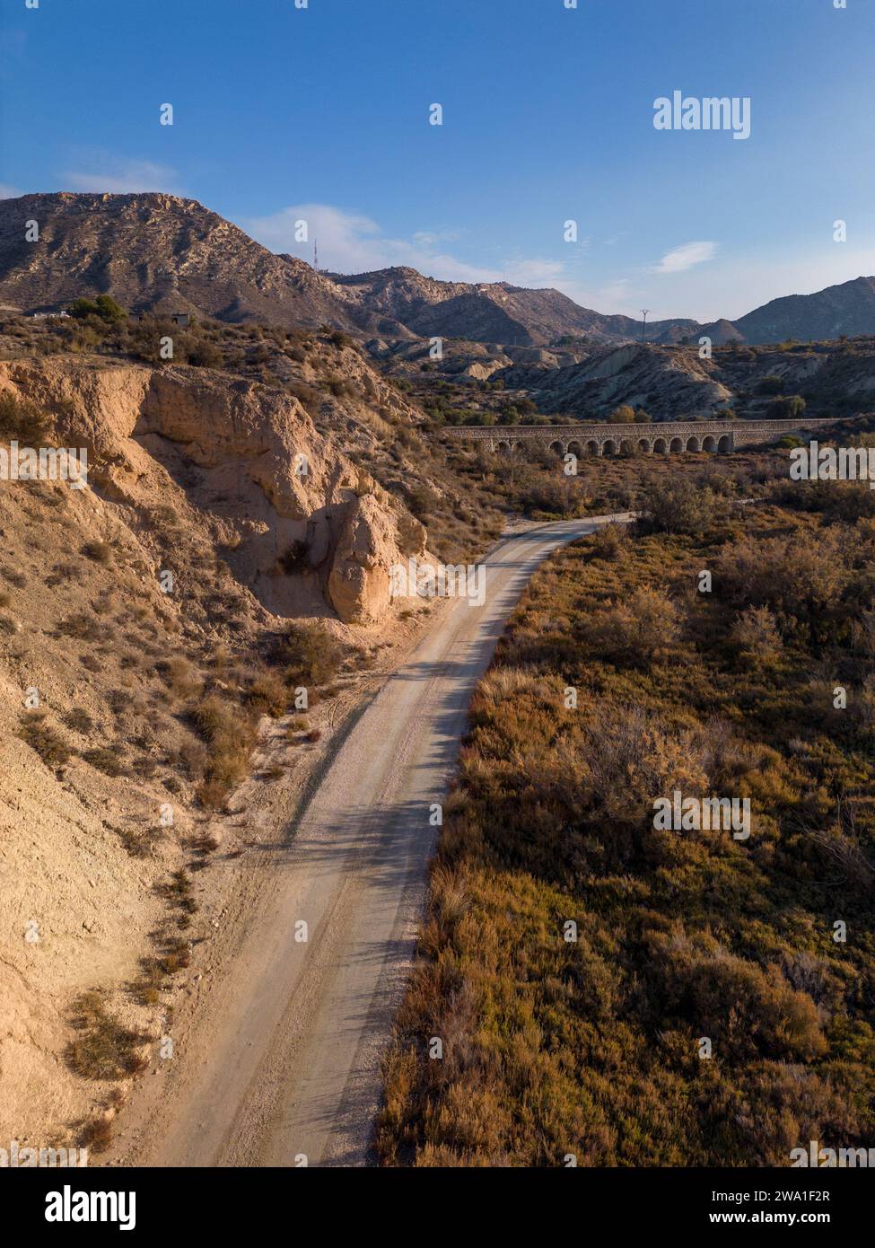 Feldweg in trockener Wüstenlandschaft mit fernen Klippen und Morgensonnenlicht, Elche, Provinz Alicante, Spanien – Stockfoto Stockfoto
