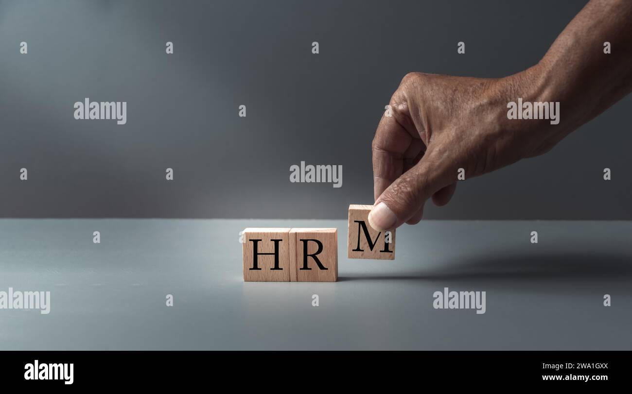 Handgeplagte Holzblöcke mit HRM oder Personalmanagement , Konzept der Humanressourcen , Führung und Diskriminierung. Grauer blauer Hintergrund , Stockfoto