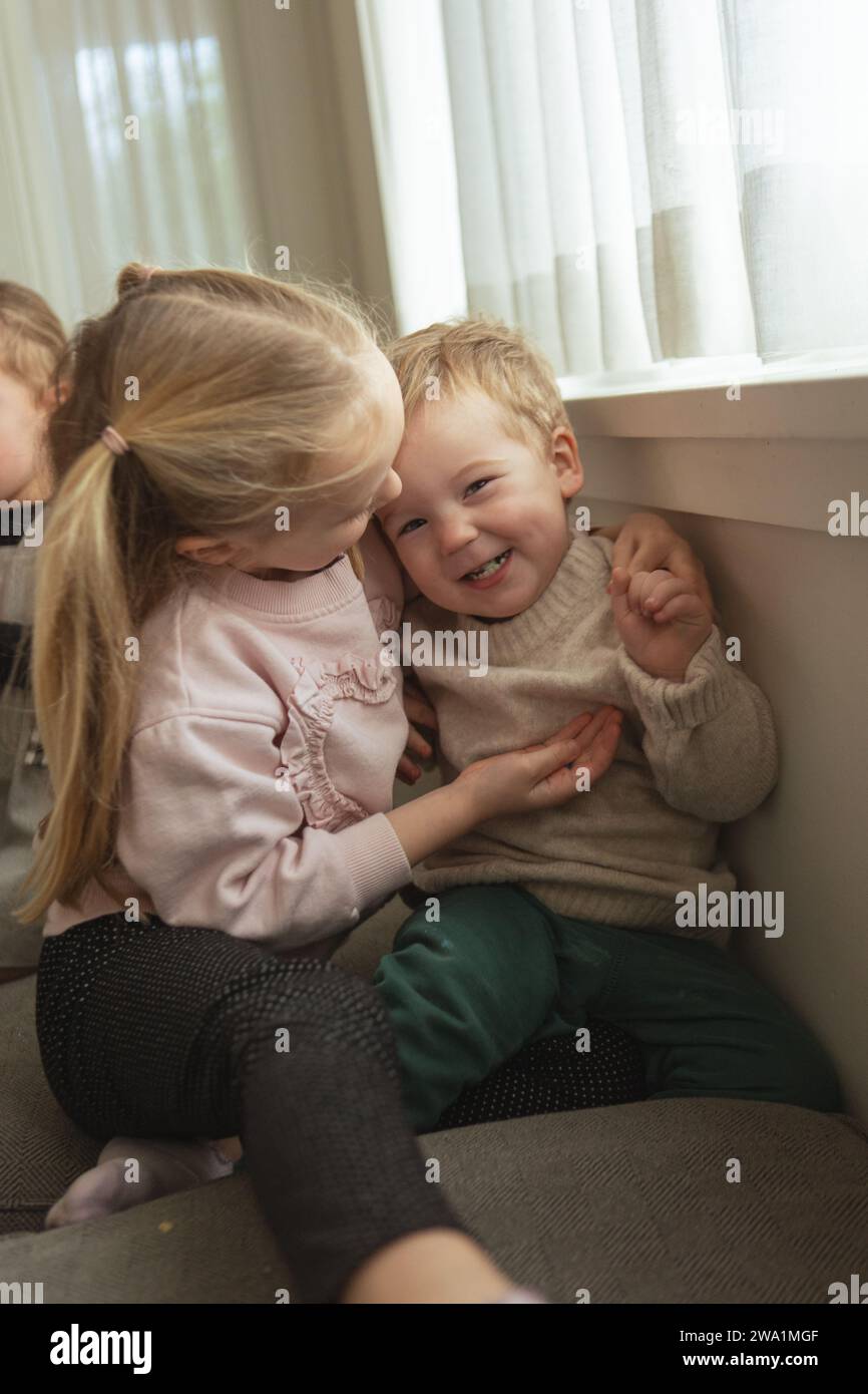 Bruder und Schwester kitzeln sich während des festlichen Familienvormittags Stockfoto