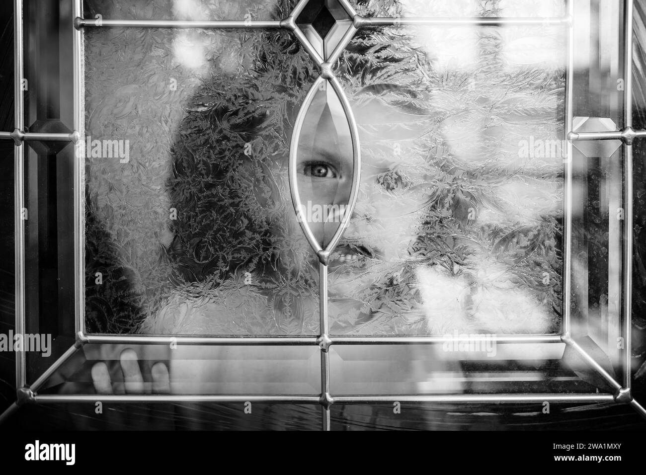 Kind, das durch ein Milchglasfenster hinausschaut Stockfoto