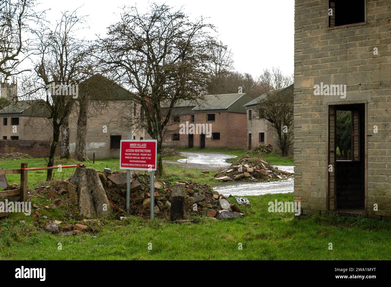 Das „verlorene Dorf“ von Imber, Salisbury Plain, Wiltshire, Großbritannien, zeigt die Kirche, Imber Court (grüne Fensterläden) und die Armee-Trainingshäuser und Warnschild. Stockfoto