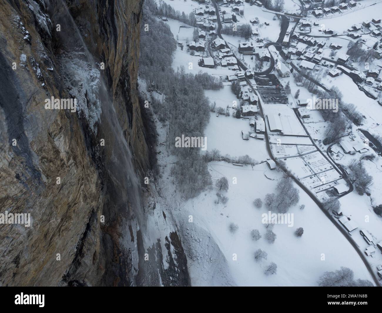 Winter-Wasserfall mit schneebedecktem schweizer Dorf Stockfoto