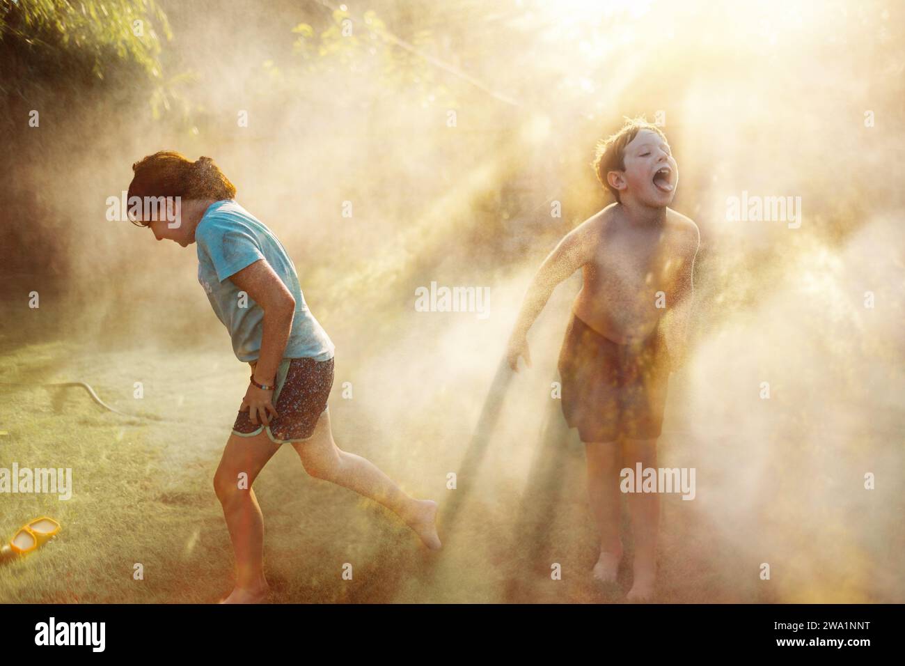 Zwei Kinder spielen im Wasser im Garten Stockfoto