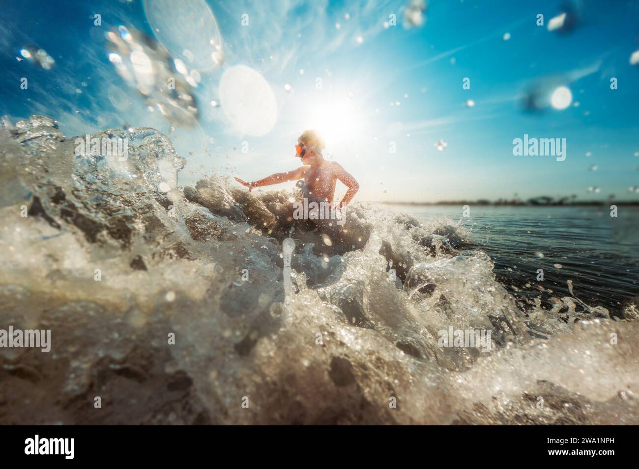 Junge, der in Meereswellen spielt, während Wasser hereinbricht Stockfoto