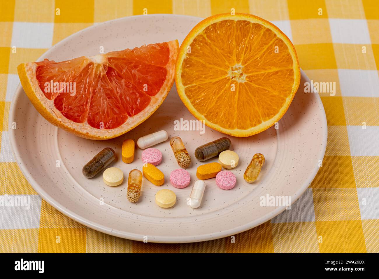 Geschnittene Orange und Grapefruit auf Teller mit Vitaminen und Nahrungsergänzungsmitteln. Bio-Obst, gesunde Ernährung und Ernährungskonzept. Stockfoto
