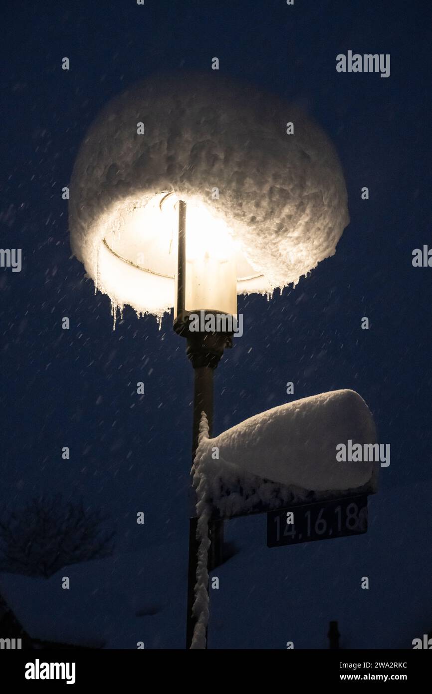 Straßenleuchte mit Motorhaube aus Neuschnee bei starkem Schneefall in der Nacht, Bayern, Deutschland Stockfoto