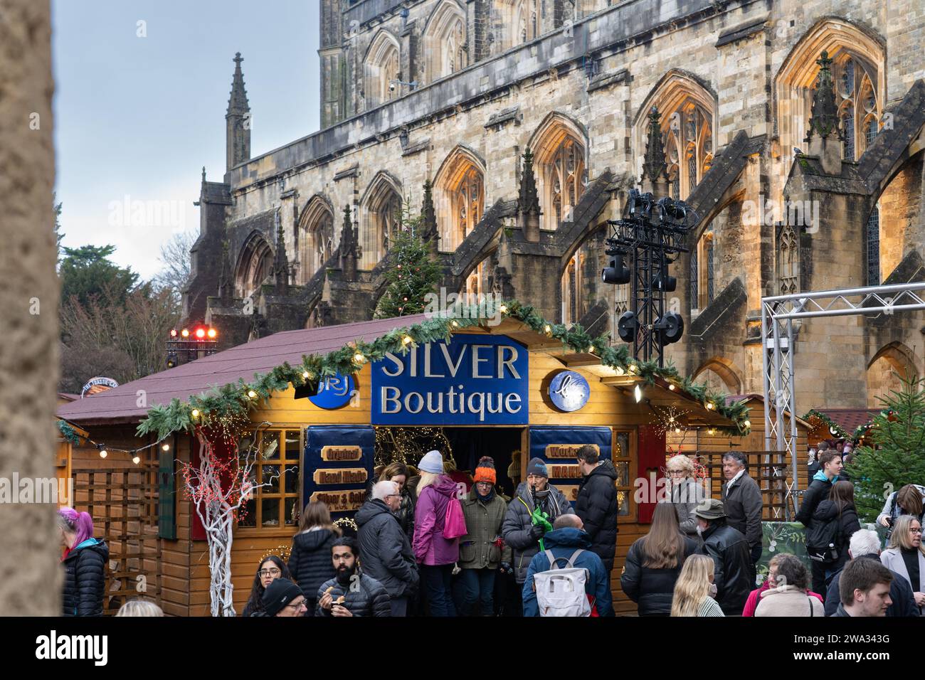 Besucher des Weihnachtsmarktes in Winchester Cathedral shoppen und in handwerklich hergestellten Hütten mit Winchester Cathedral im Hintergrund stöbern. England Stockfoto