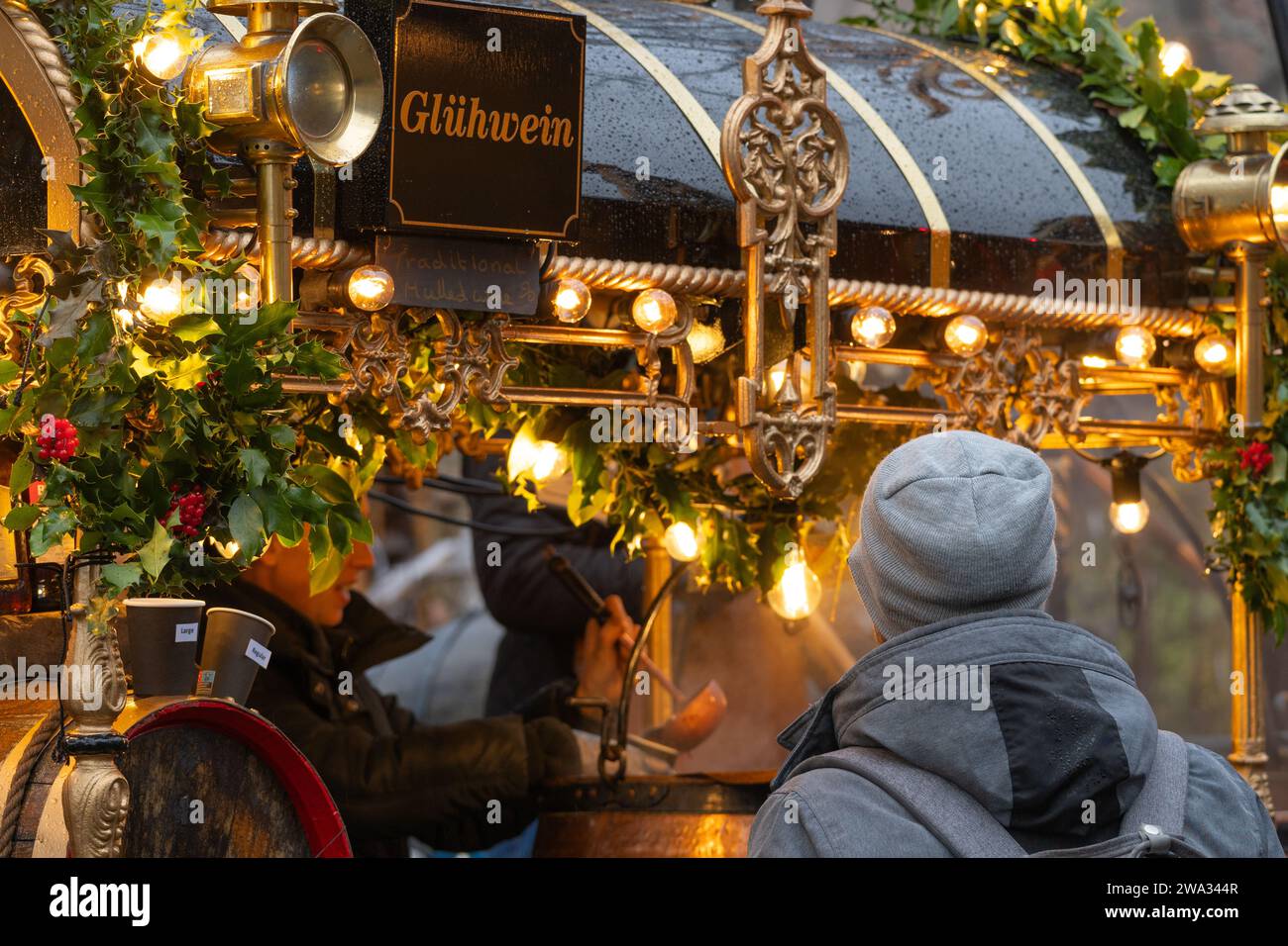 Eine Frau, die traditionellen Glühwein (Glühwein) in eine Tasse für einen Kunden auf dem Winchester Cathedral Christmas Market in Hampshire, Großbritannien, ausschöpft Stockfoto