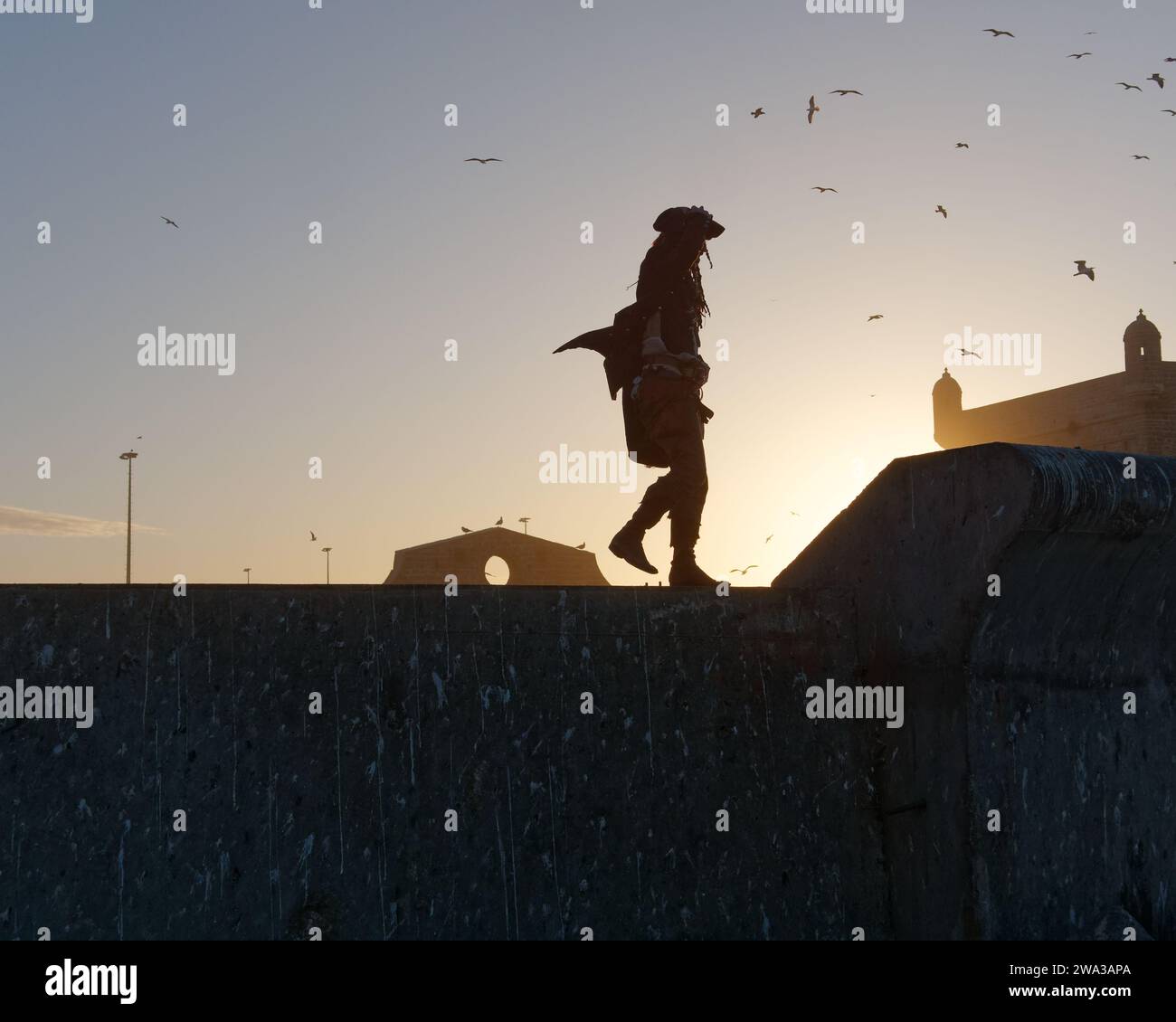 Mann in Piratenkostüm geht an einem Winterabend in Essaouira, Marokko, am 1. Januar 2024 durch die Stadtmauern am Fort Stockfoto