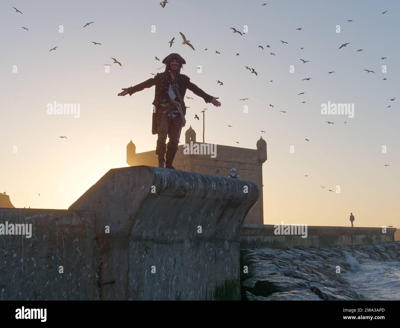 Mann in Piratenkostüm geht an einem Winterabend in Essaouira, Marokko, am 1. Januar 2024 durch die Stadtmauern am Fort Stockfoto