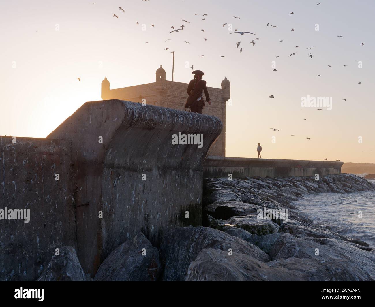 Mann in Piratenkostüm geht an einem Winterabend in Essaouira, Marokko, am 1. Januar 2024 durch die Stadtmauern am Fort Stockfoto