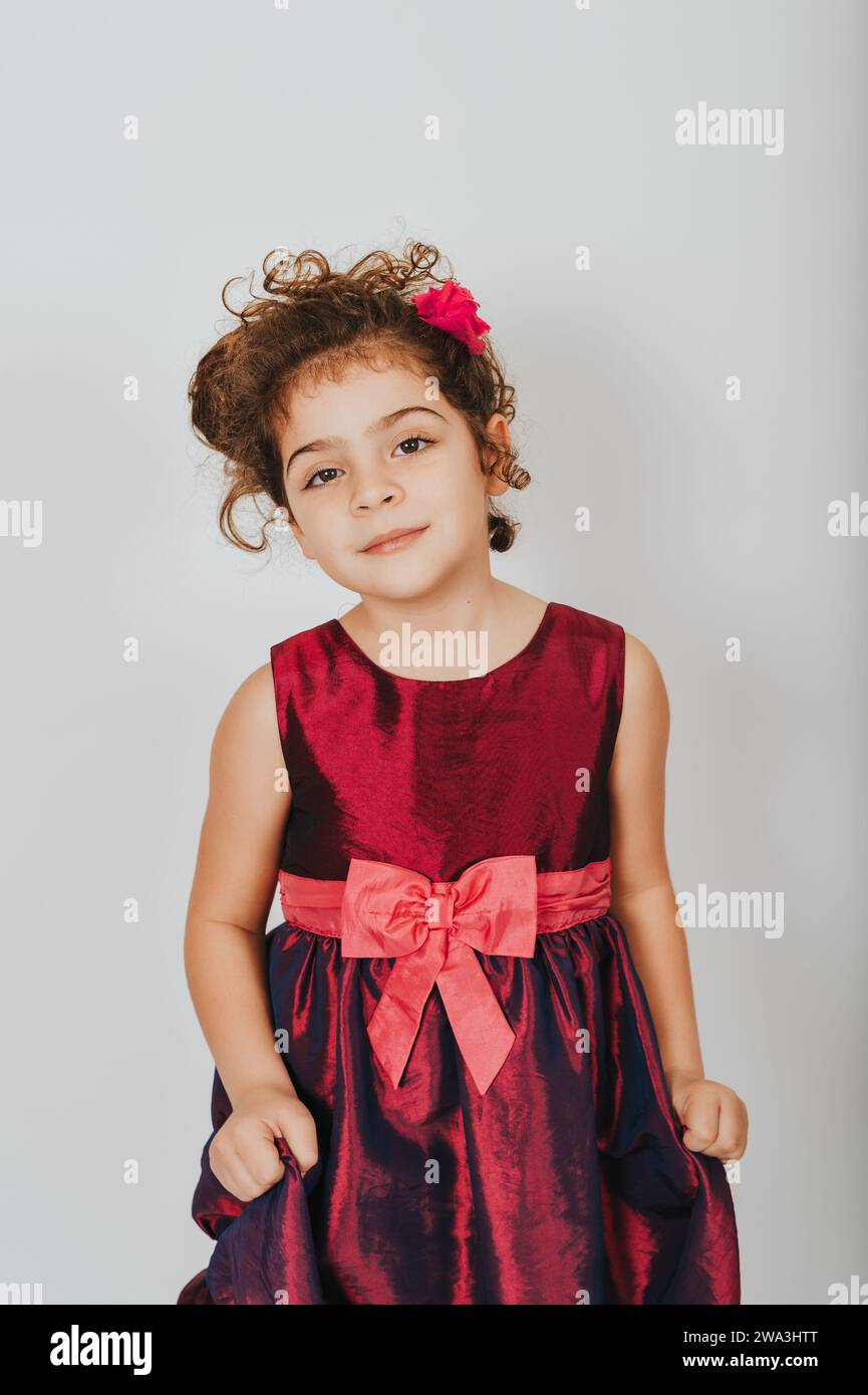 Studio-Aufnahme eines 5-jährigen Mädchens mit lockigen Haaren in Partykleid Stockfoto