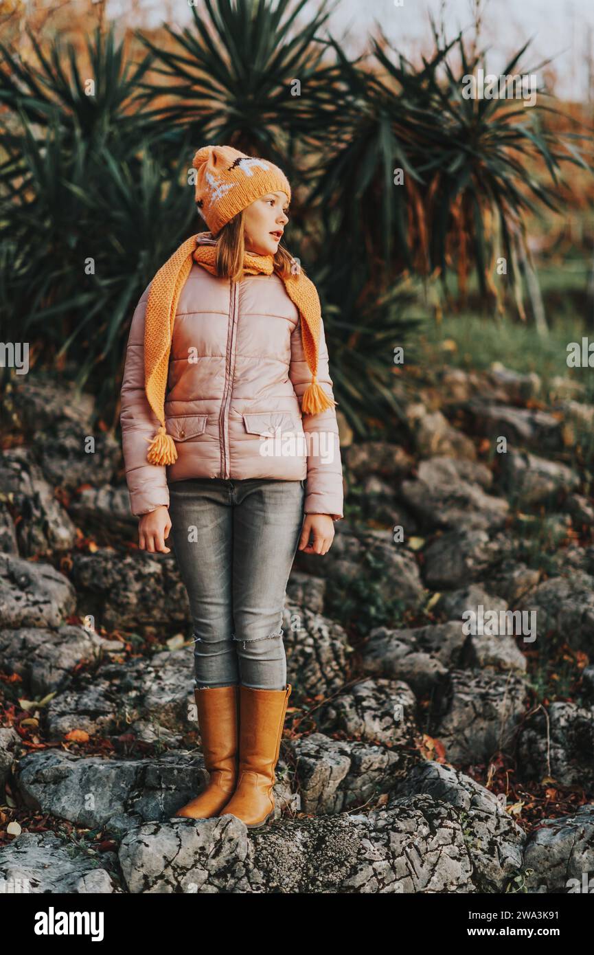 Außenporträt eines hübschen 10-jährigen Mädchens mit rosa Jacke und braunen, hohen Lederstiefeln Stockfoto