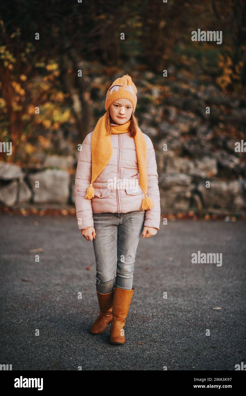 Außenporträt eines hübschen 10-jährigen Mädchens mit rosa Jacke und braunen, hohen Lederstiefeln Stockfoto