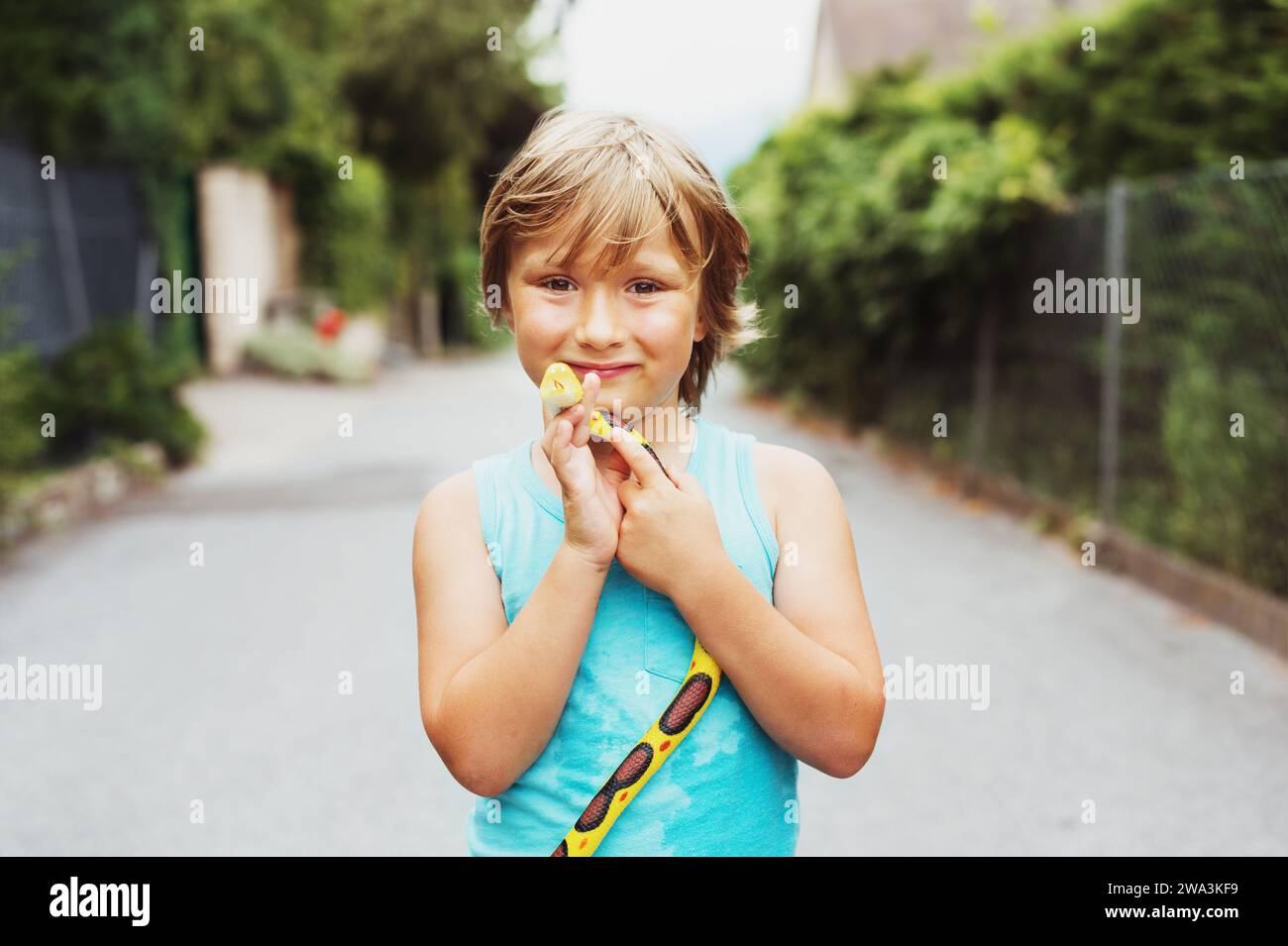 Außenporträt eines lustigen kleinen Jungen, der mit Gummischlangenspielzeug in der Nachbarschaft spielt Stockfoto