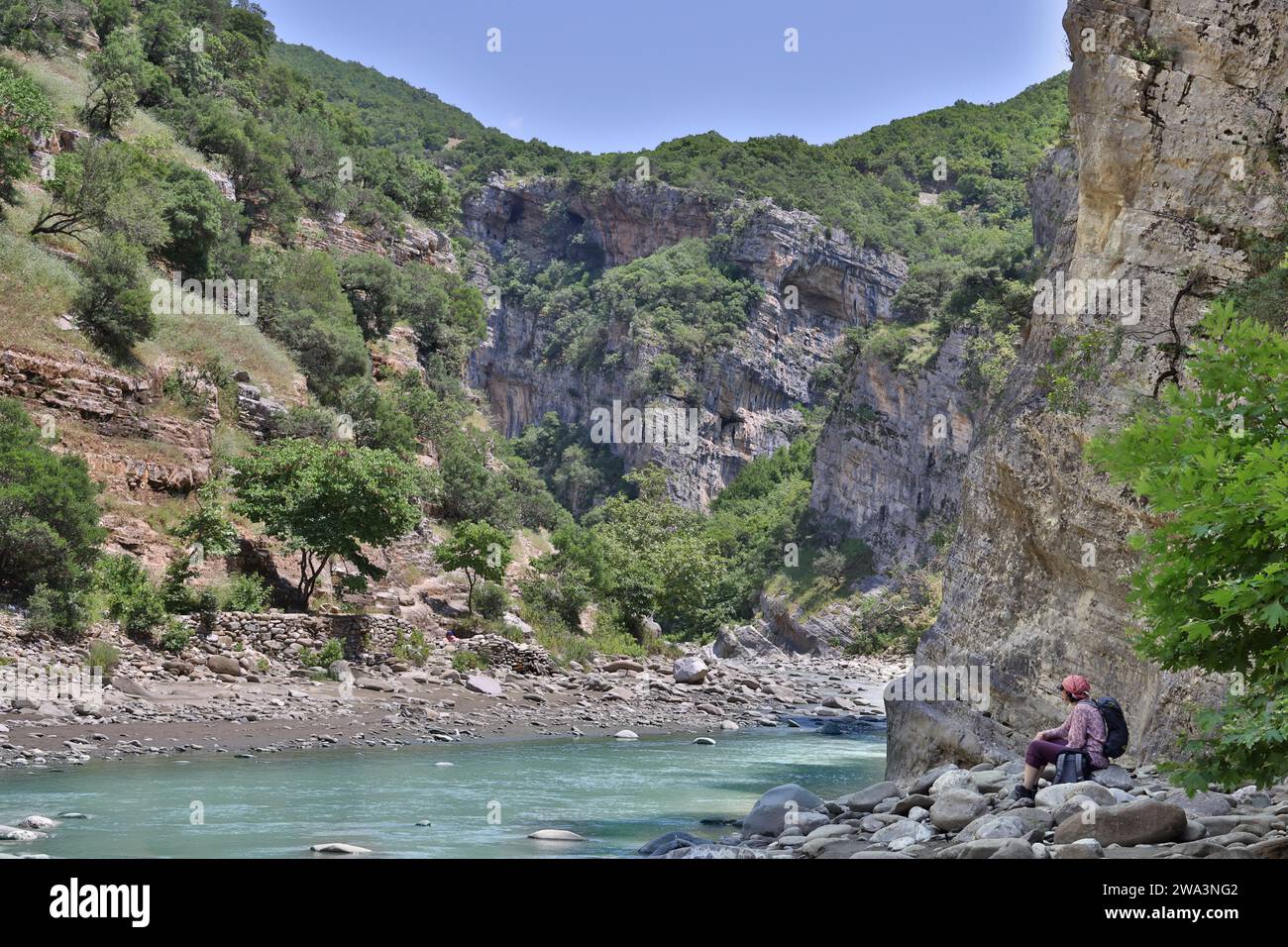Eine Frau in Wanderkleidung sitzt auf großen Steinen am Anfang des Lengarica Canyon, Benje, Albanien, Europa Stockfoto