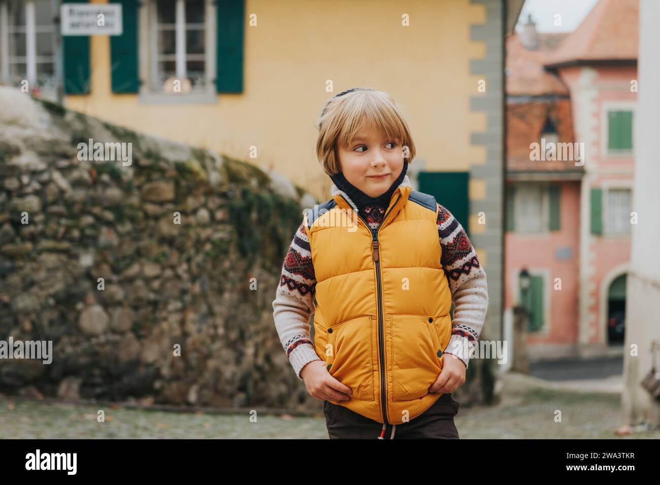 Außenporträt eines süßen kleinen Jungen von 4-5 Jahren, der eine warme gelbe Weste trägt Stockfoto