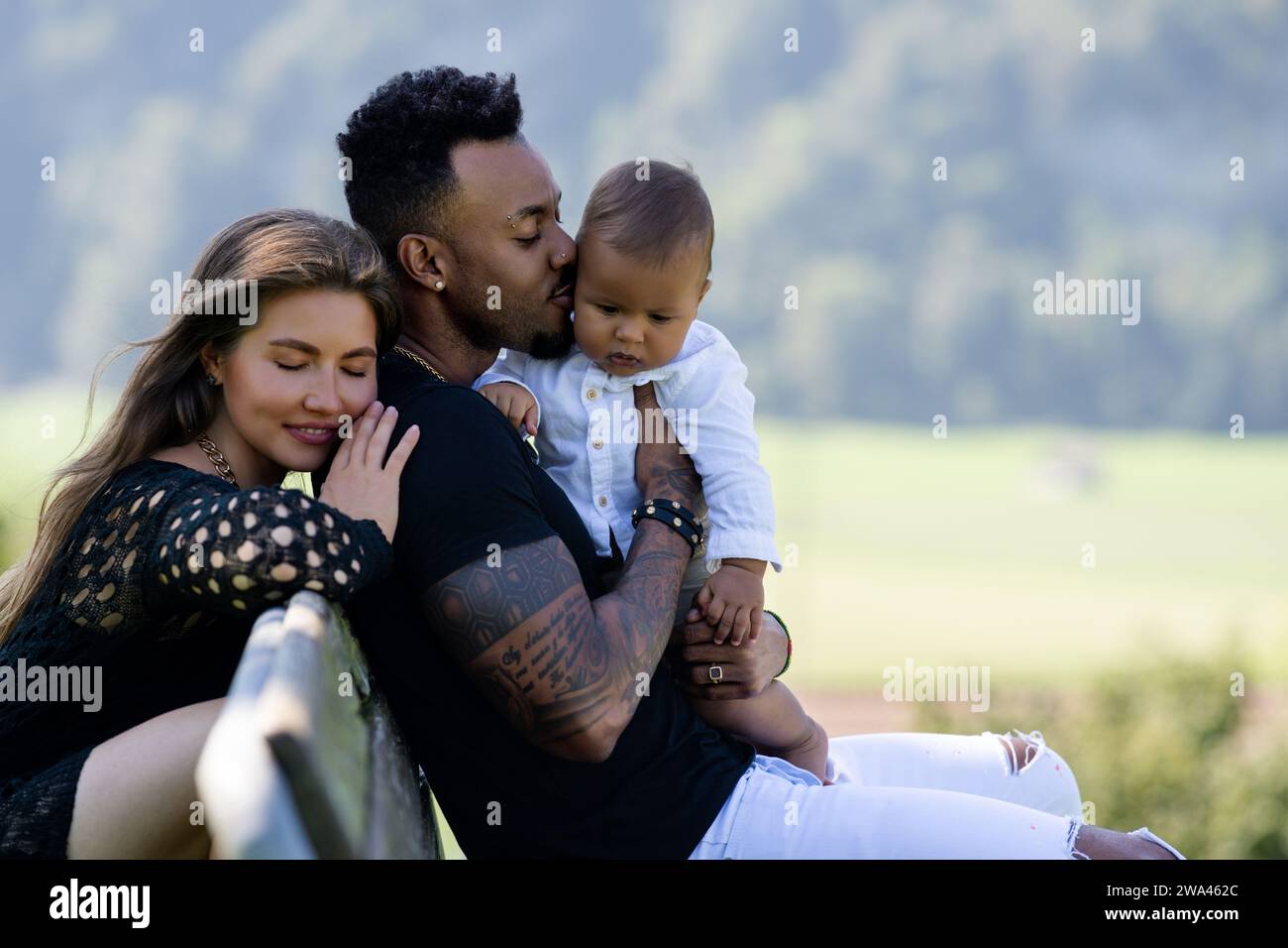 Multiethnische Eltern birassisches Baby im Park. Multirassisches Paar im Außenporträt. Birassisches Babykind mit Eltern im Hinterhof. Vielfältige Familie. Afrikanisch Stockfoto